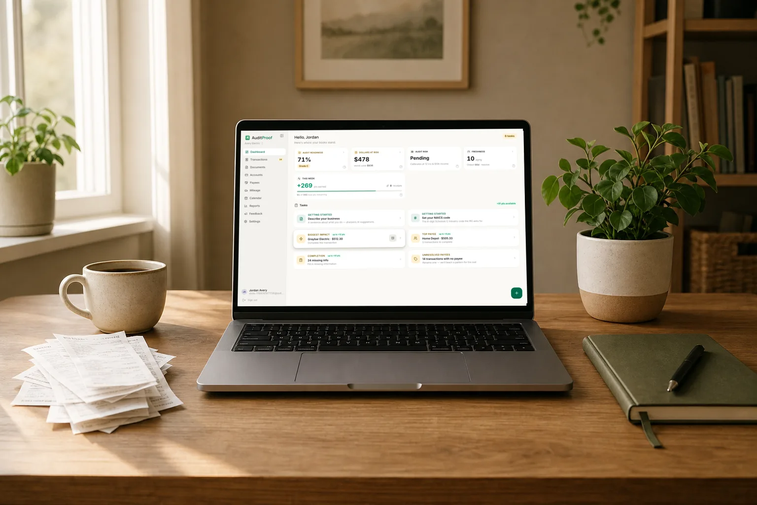A tidy desk with a laptop showing AuditProof monthly reports beside a stack of receipts